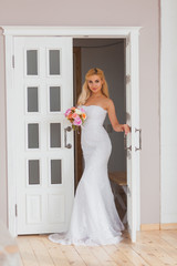 Portrait of a beautiful blonde bride with bouquet in an interior light, wedding concept
