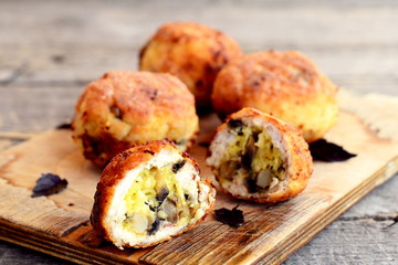 Fried meat patties filled with cheese and fried mushrooms on board and on wooden table. Homemade filled patties prepared from minced Turkey meat. Closeup