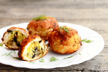 Fried meat patties stuffed with cheese and fried mushrooms on plate on wooden background. Homemade stuffed patties prepared from minced meat. Closeup