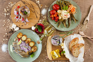 Other meat, fish, cheese dishes and appetizers with herbs, spices, oil and wine on a wooden background