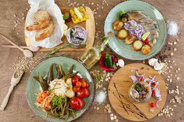 Other meat, fish, cheese dishes and appetizers with herbs, spices, oil and wine on a wooden background