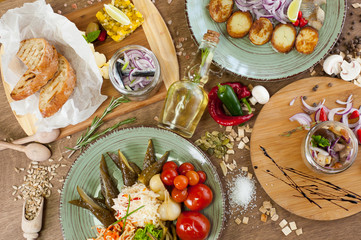 Other meat, fish, cheese dishes and appetizers with herbs, spices, oil and wine on a wooden background
