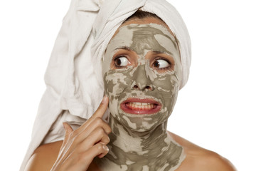 beautiful nervous woman with a mud mask on her face