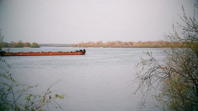 Long cargo barge sailing down Dnieper river in Ukraine near Kiev