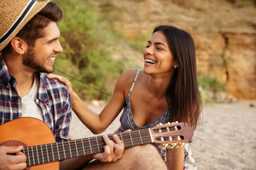 Man playing guitar for his girlfriend sitting at the tent