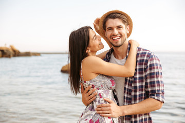 Happy young hipster couple standing at the beach and hugging