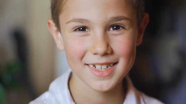 portrait of 8 year old boy with big eyes smiling at the camera in slow-motion
