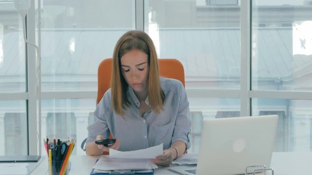 Young busy attractive business woman working in modern office. Timelapse. 4K.
