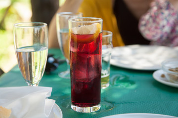 crystal glass full of typical spanish summertime drink, wine with soda, ice and lemon slice, on green paper tablecloth restaurant
