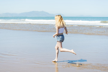 Fototapeta na wymiar Woman running down the beach in summer season.