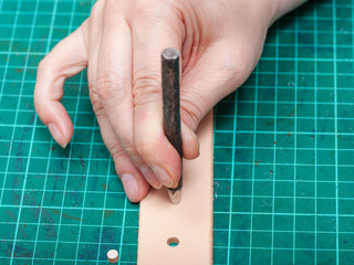 Obraz premium punching hole in new belt with steel punch