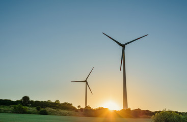 Two wind turbines at sunrise or sunset