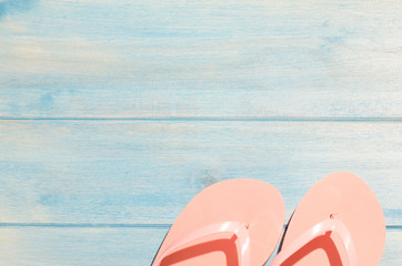 pink flip flops on blue wooden table with sunlight