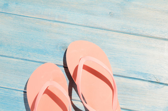 pink flip flops on blue wooden table with sunlight