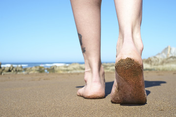 Female feet walking on beach closeup.