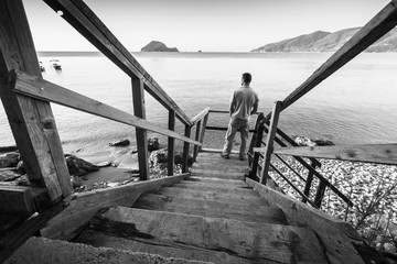 Young man stands on coastal wooden stairway