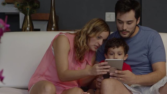Young couple teaching son how to use tablet