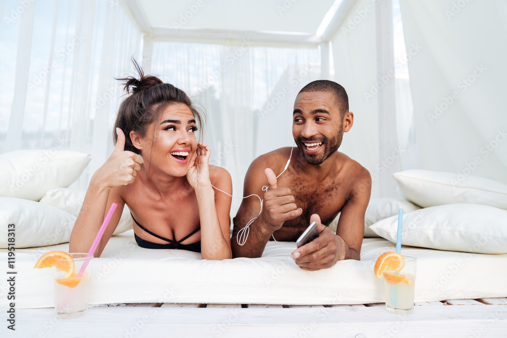 Poster young happy couple in love listening to music with earphones