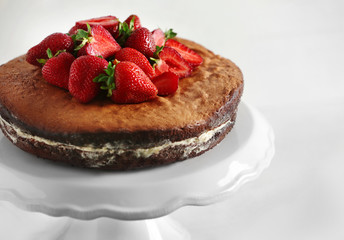 Delicious cake decorated with strawberry on white stand