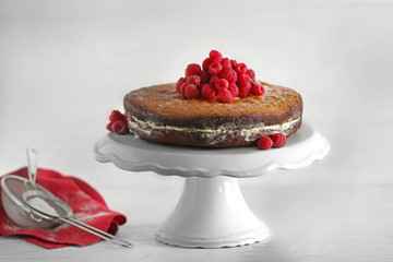 Delicious cake decorated with raspberry on white stand