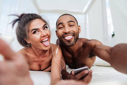 Cheerful couple making selfie and showing tongues at the beach