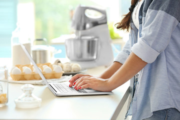 Girl with laptop on kitchen. Food blogger concept