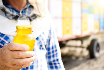 Man holding bottle of honey on mobile apiary background