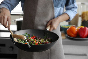 Female hand mixing vegetables in pan closeup