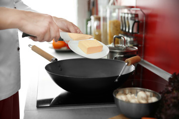Female hand putting butter in pan closeup