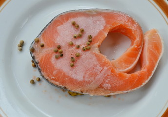 raw frozen salmon dressing pepper on plate