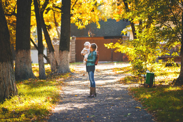 Fototapeta premium Young mother holding her daughter in the autumn park