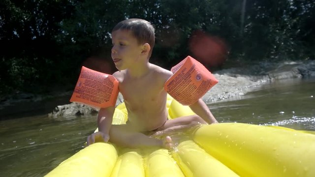Young Boy Having Fun on Inflatable Mattress in the Mountain River