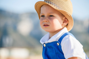 Cute blond boy in hat and blue overall