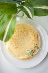 Delicious russian pancakes on a plate under a bouquet of flowers