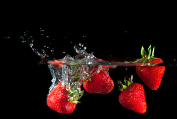 Strawberries splashing into water
