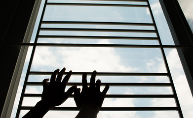 Silhouette of hands hold the window, sky background.