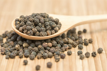 Close-up black pepper on a wood spoon