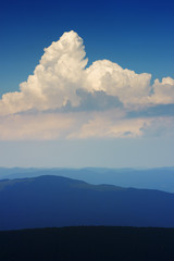 Obraz premium Mountain landscape in haze. Beautiful clouds in sky above mountain ridge. Stormy weather. Panorama.