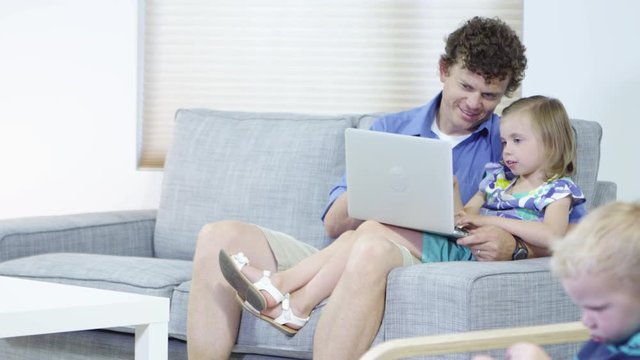 Father daughter and son using laptop in the living room