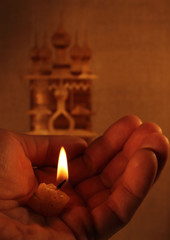 Burning candle in hands on the background of the Church