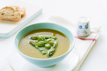 Asparagus soup in a bowl topped with fresh basil