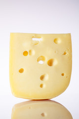 a piece of Swiss cheese with holes large triangular-shaped forms on a gray background with a gradient. food background. one piece of European cheese