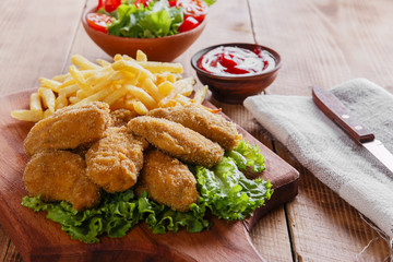 chicken wings fried in breadcrumbs with sauce and french fries