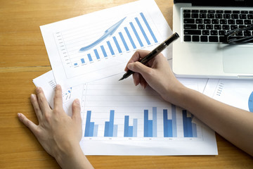 Photo of human hands holding pen and marking graphs monitoring in documents