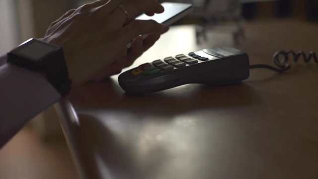 Man using smart watch to express pay on a wooden table