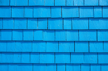 Abstract background of blue shingles on the side of a brightly painted old-fashioned wood house