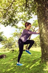 young woman excercise against tree