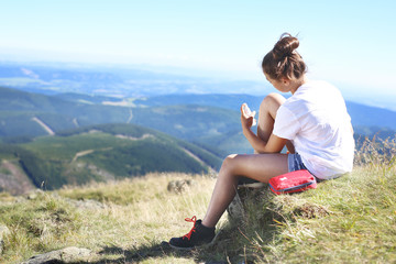 Turystka odkaża ranę na kolanie siedząc na zboczu górskiego szlaku.