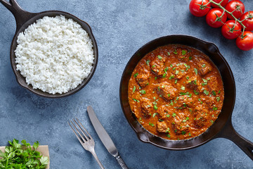 Traditional Madras butter Beef spicy slow cook lamb food with rice and tomatoes in cast iron pan on...