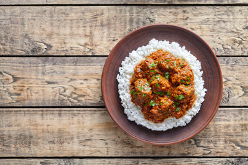 Madras butter Beef spicy slow cook lamb food with rice in clay dish on vintage wooden table background. Delicious India culture restaurant dish.